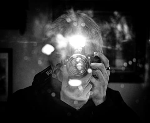 Calvin’s first photographer selfie: a black-and-white mirror shot behind a camera, its flash flaring